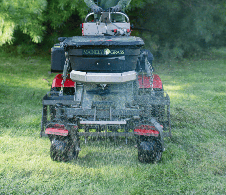 Aeration and overseeding technician spreading seed on lawn
