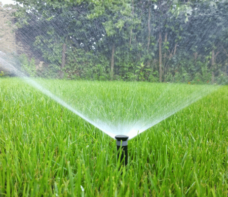 An irrigation system watering a summer lawn