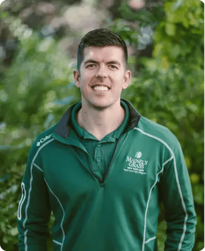 Mainely Grass lawn care technician in uniform, smiling outdoors