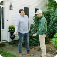 A Mainely Grass technician discussing lawn care services with a homeowner, demonstrating expert customer service.