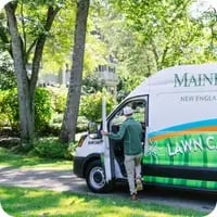 A Mainely Grass technician stepping into a branded service van, ready to provide expert lawn care services.