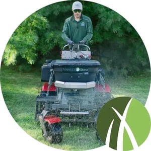 Lawn care professional performing aeration and overseeding to promote healthy grass growth.