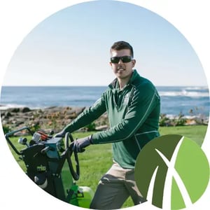 A Mainely Grass lawn care technician operating professional equipment near the coast, delivering expert lawn care treatments.