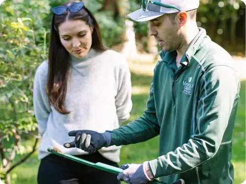 A Mainely Grass technician explaining a soil sample analysis to a customer, ensuring optimal lawn health.
