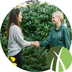 Organic lawn care expert greeting a satisfied customer with a handshake in a lush green garden