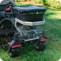 A Mainely Grass technician performing aeration and overseeding services, enhancing lawn health and promoting lush, green grass.