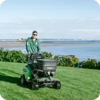 A lawn care professional applying treatment on a lush coastal property, showcasing expert lawn care services for healthy, green grass.