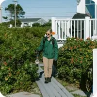 A Mainely Grass technician providing lawn pest control services at a coastal home for ticks and mosquitoes.